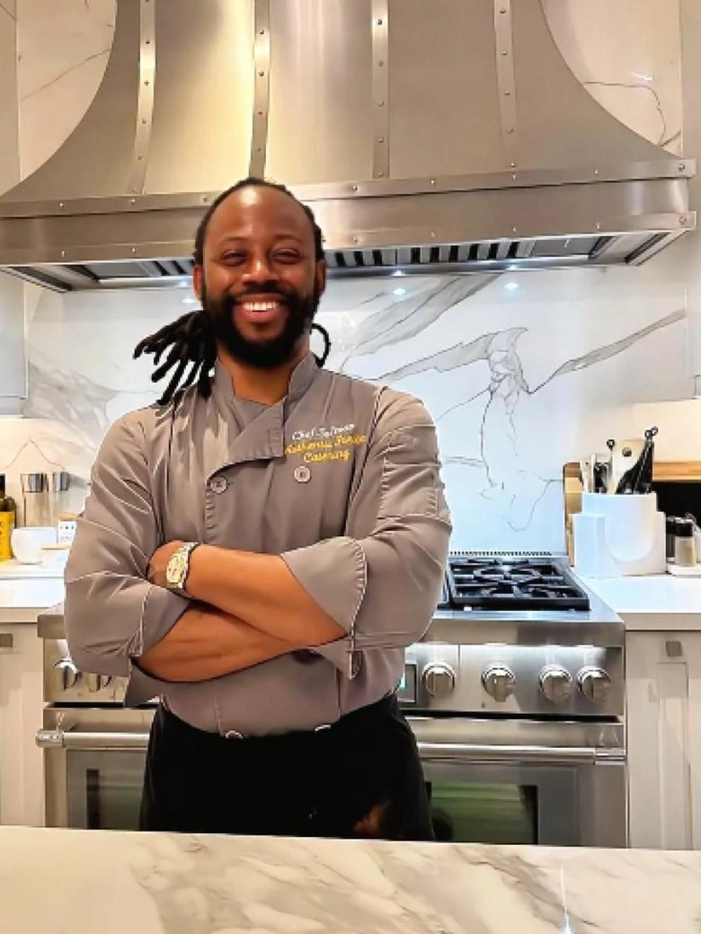 Christopher Salmon in a grey chef jacket, standing in front of a range